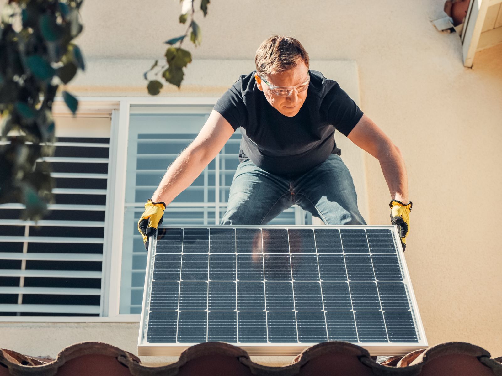 Monteur setzt ein Photovoltaikmodul an einer Fassade